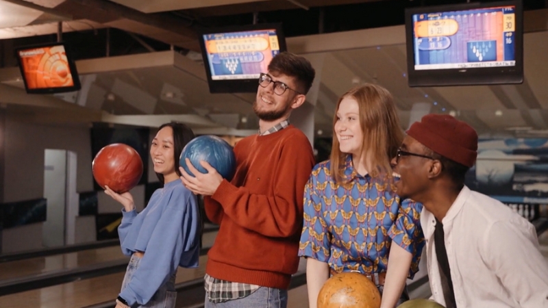 A group of friends holding bowling balls, illustrating the concept of average bowling score